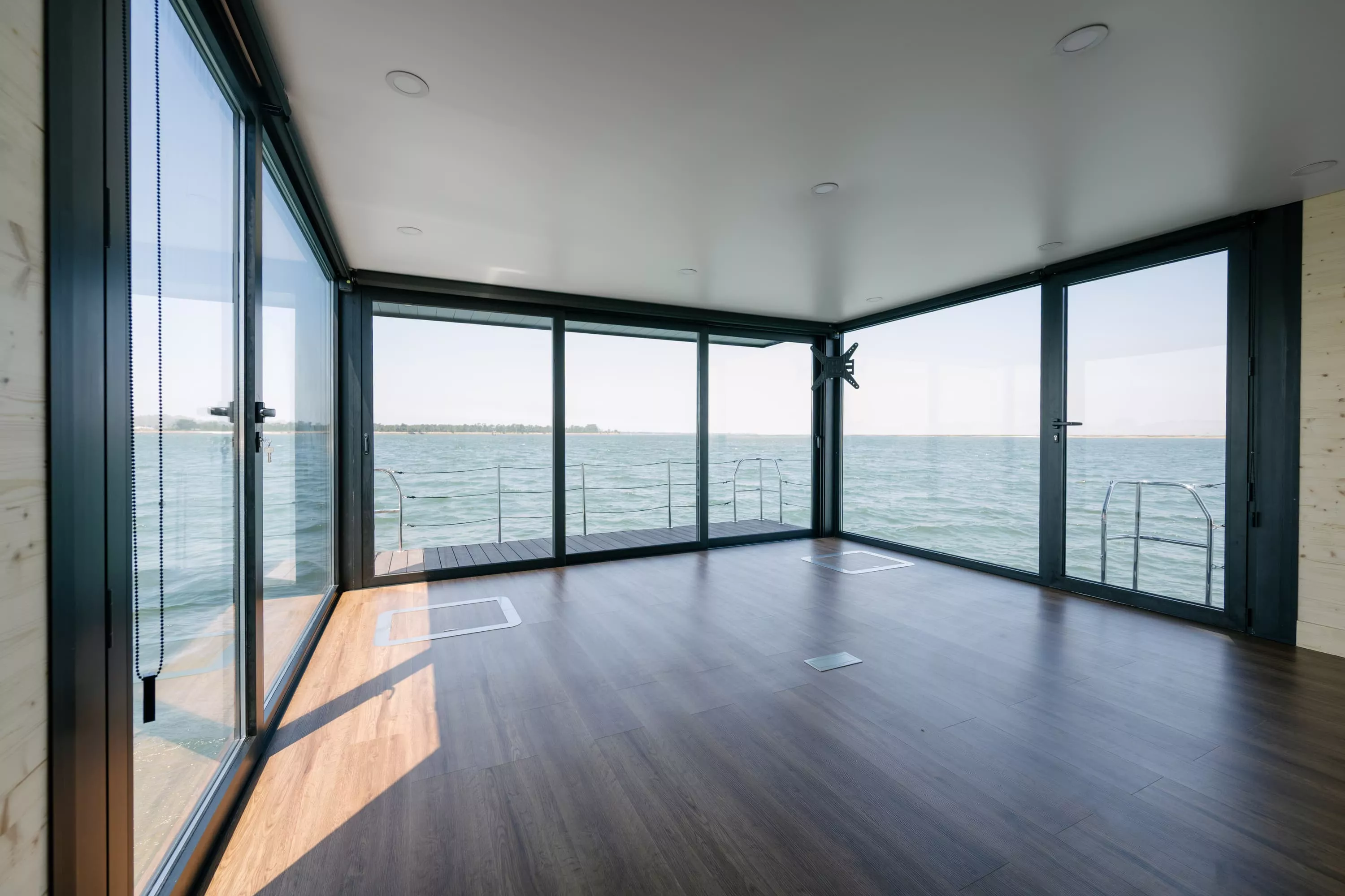 Empty interior of a floating office with panoramic glass walls overlooking the water